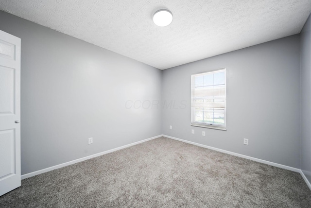 carpeted spare room featuring baseboards and a textured ceiling