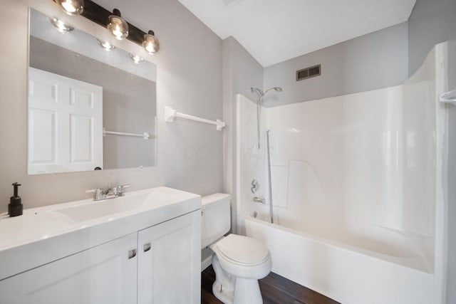 bathroom with visible vents, shower / tub combination, wood finished floors, vanity, and toilet