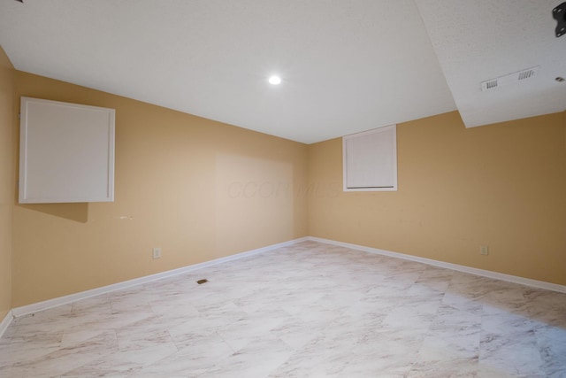 empty room with baseboards, marble finish floor, vaulted ceiling, and visible vents