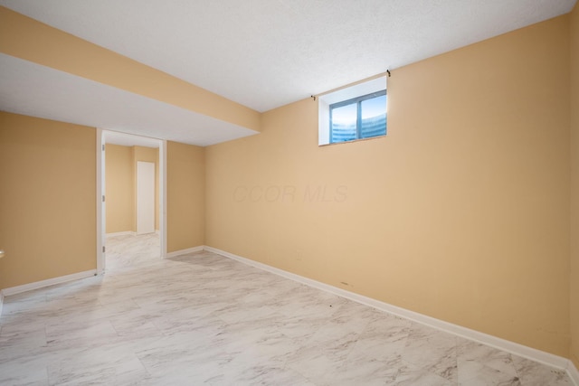 below grade area with baseboards and marble finish floor