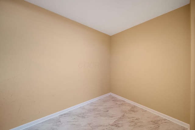 unfurnished room featuring baseboards, lofted ceiling, and marble finish floor