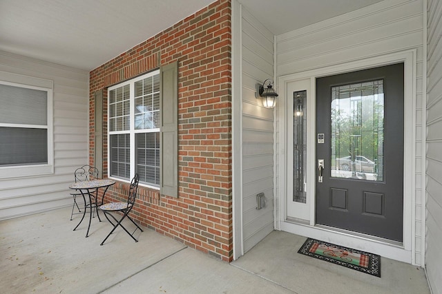 entrance to property with a porch and brick siding