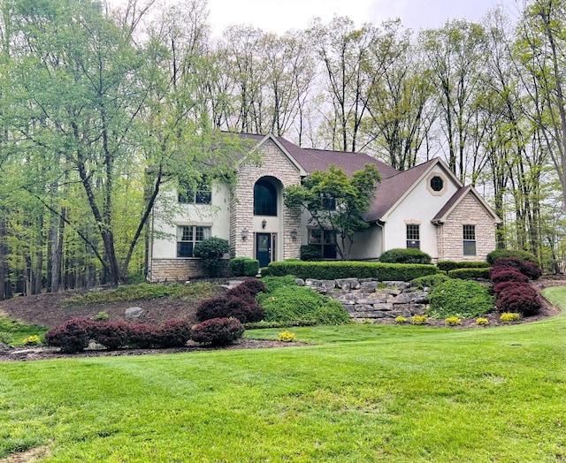 view of front facade with a front lawn, stone siding, and stucco siding
