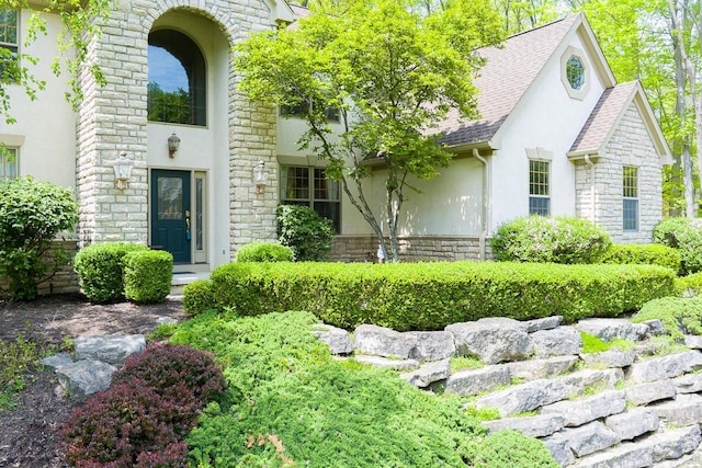 8884 Filiz Ln, Powell, OH 43065 - view of exterior entry featuring stucco siding, stone siding, and roof with shingles