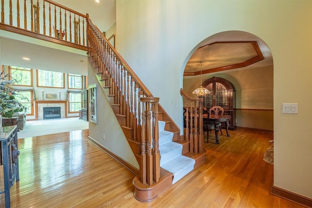8884 Filiz Ln, Powell, OH 43065 - stairs featuring arched walkways, a chandelier, a fireplace, and wood finished floors