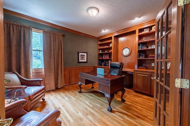 8884 Filiz Ln, Powell, OH 43065 - office area featuring ornamental molding, a textured ceiling, wainscoting, light wood-style floors, and built in shelves