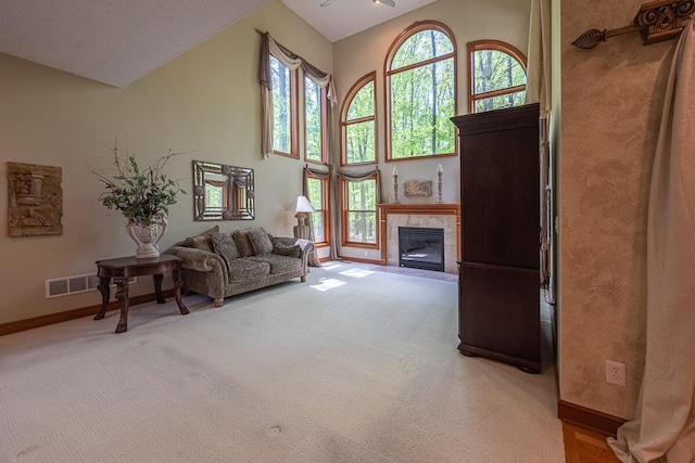 8884 Filiz Ln, Powell, OH 43065 - living room featuring light carpet, healthy amount of natural light, baseboards, a tiled fireplace, and high vaulted ceiling