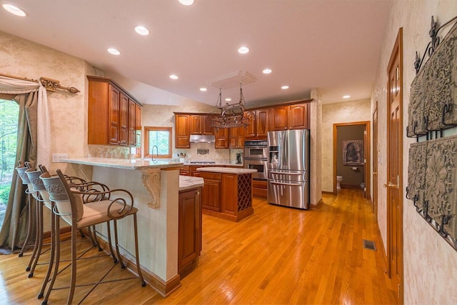 8884 Filiz Ln, Powell, OH 43065 - kitchen with appliances with stainless steel finishes, under cabinet range hood, light wood-style floors, recessed lighting, and lofted ceiling