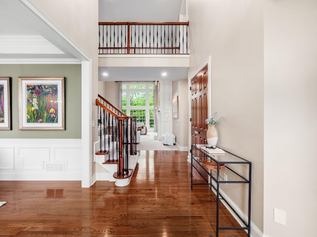 entryway featuring stairs, wood finished floors, baseboards, and crown molding
