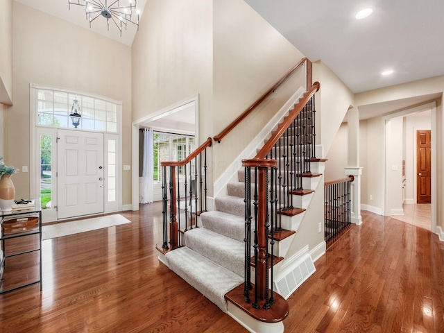 foyer entrance with wood finished floors, a towering ceiling, baseboards, recessed lighting, and stairway