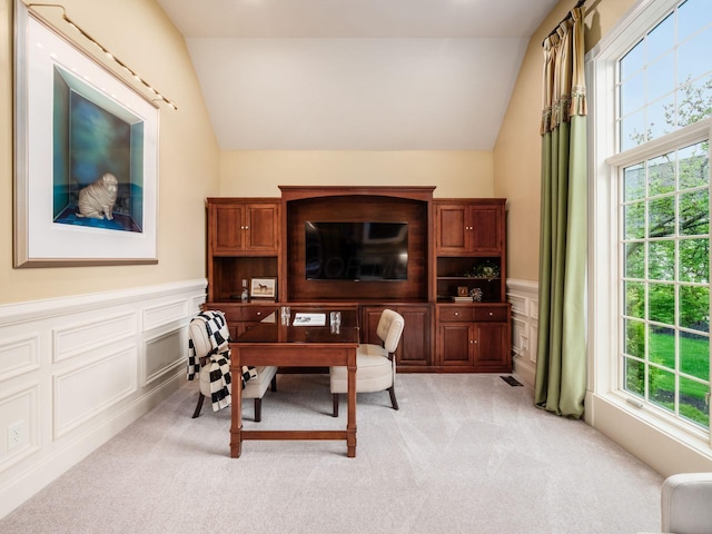 office space with a decorative wall, lofted ceiling, light colored carpet, and a wainscoted wall