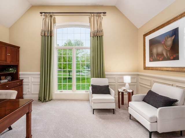 living area with lofted ceiling, wainscoting, carpet floors, and a decorative wall