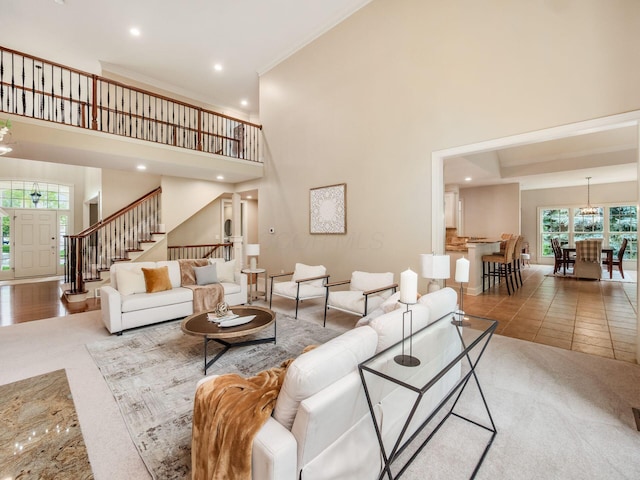 living area with stairway, a high ceiling, crown molding, recessed lighting, and tile patterned floors