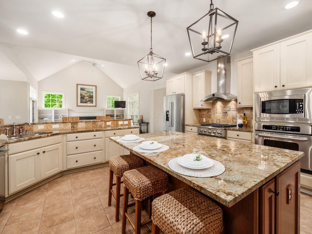 kitchen with wall chimney exhaust hood, stainless steel appliances, a sink, a chandelier, and decorative backsplash