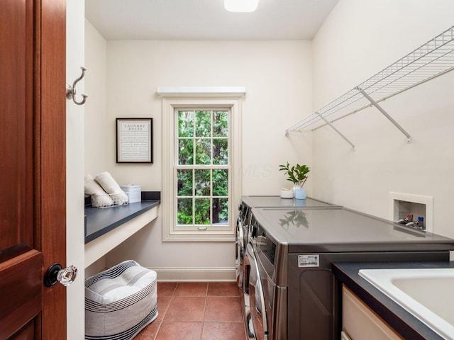 laundry room featuring washing machine and dryer, baseboards, and dark tile patterned flooring