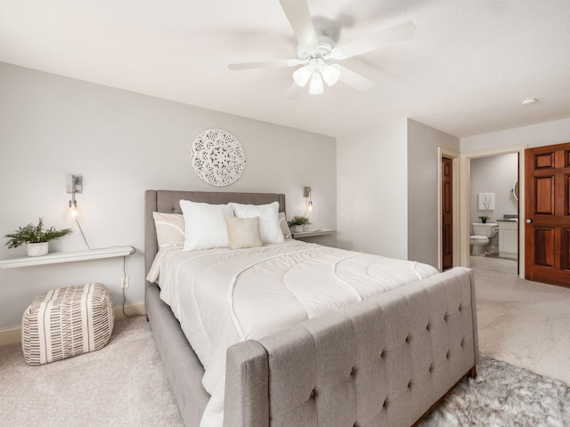 carpeted bedroom with ensuite bathroom, ceiling fan, and baseboards