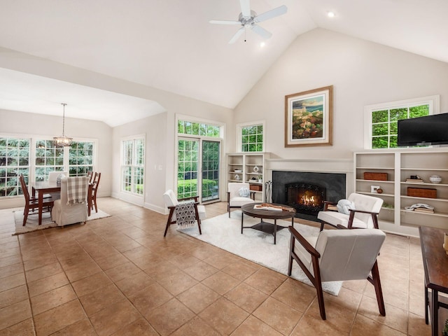 living area with a ceiling fan, high vaulted ceiling, a lit fireplace, and baseboards