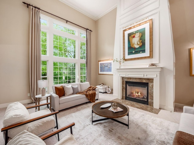 living room with ornamental molding, a high end fireplace, baseboards, and carpet