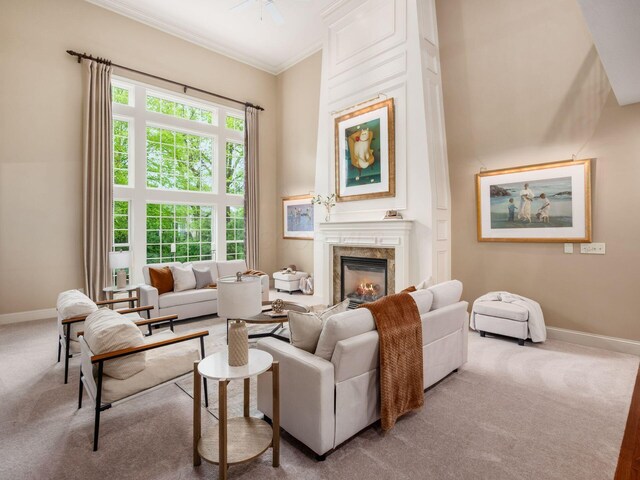 carpeted living area with ornamental molding, baseboards, a premium fireplace, and ceiling fan