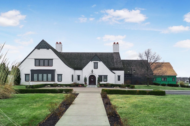 french country inspired facade featuring a chimney and a front yard