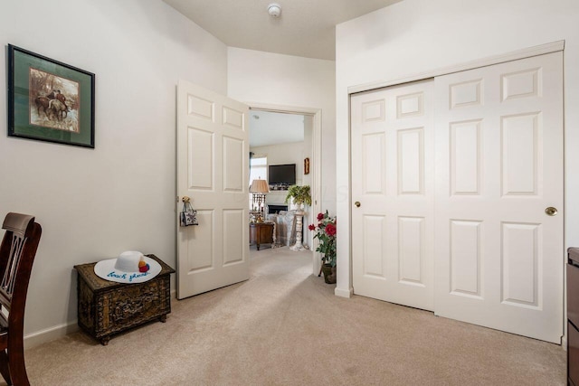 interior space featuring a fireplace, baseboards, light colored carpet, and a closet