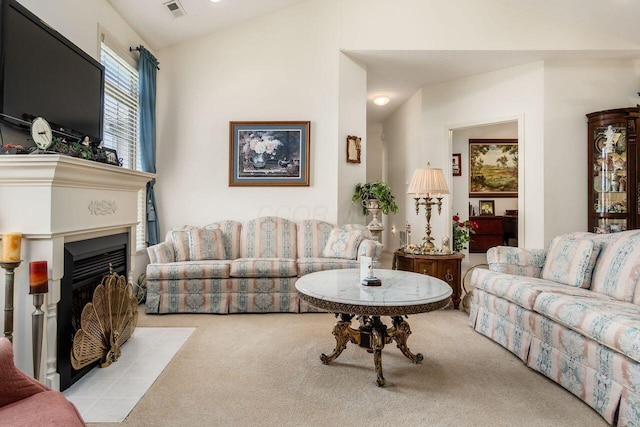 carpeted living area with a fireplace with flush hearth, lofted ceiling, and visible vents