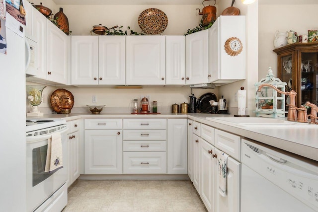 kitchen with white appliances, white cabinets, a sink, and light countertops