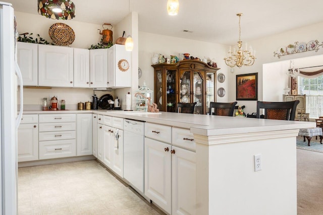 kitchen featuring light countertops, white cabinets, a peninsula, a notable chandelier, and white appliances