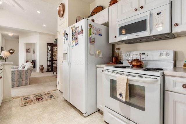 kitchen featuring light countertops, white cabinets, vaulted ceiling, and white appliances
