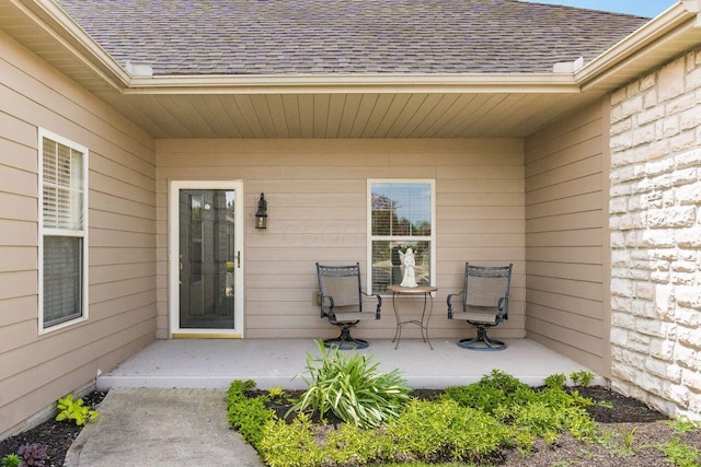 property entrance featuring a patio and a shingled roof