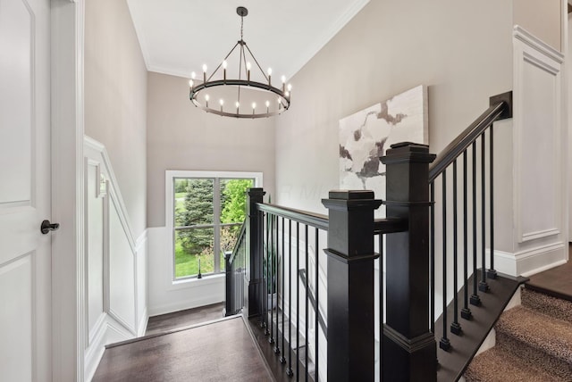 stairway featuring ornamental molding, an inviting chandelier, and wood finished floors