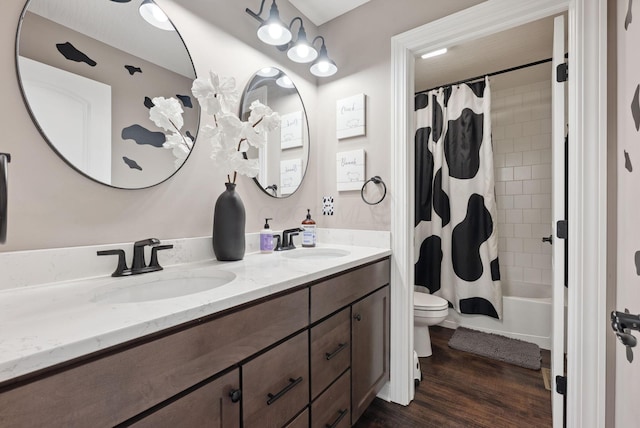 full bathroom featuring double vanity, toilet, wood finished floors, and a sink