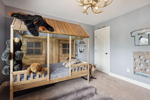 carpeted bedroom featuring baseboards and a chandelier