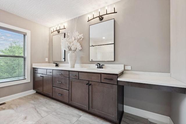 bathroom featuring a sink, double vanity, walk in shower, and baseboards
