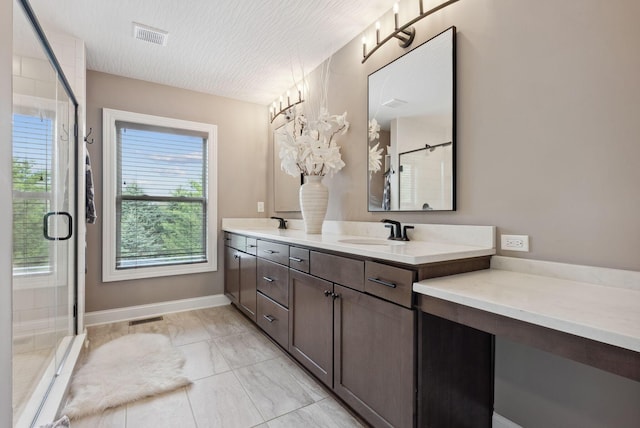 bathroom featuring a stall shower, visible vents, a sink, and double vanity