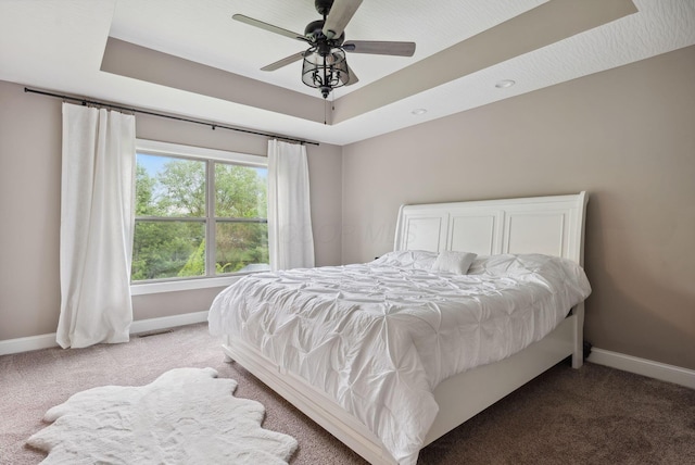 bedroom with a raised ceiling, carpet floors, baseboards, and visible vents