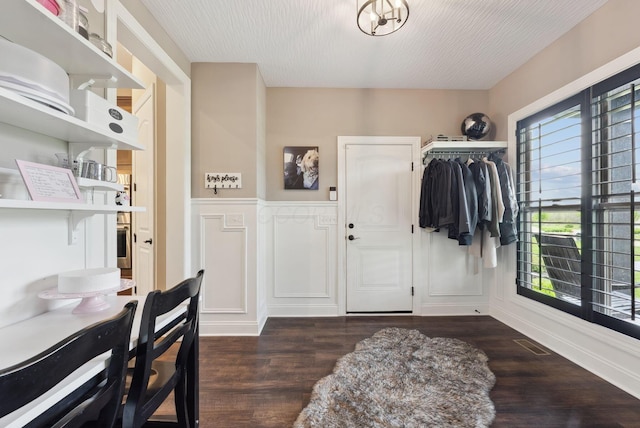 foyer with dark wood finished floors, wainscoting, and visible vents