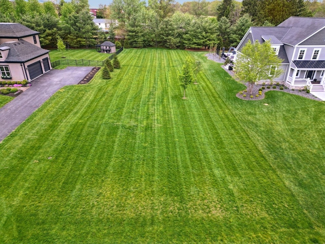 view of yard with fence, a garage, and aphalt driveway