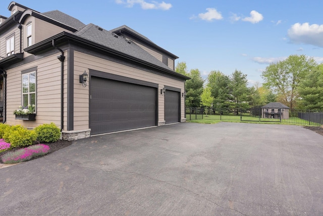 view of side of property with roof with shingles, fence, and driveway