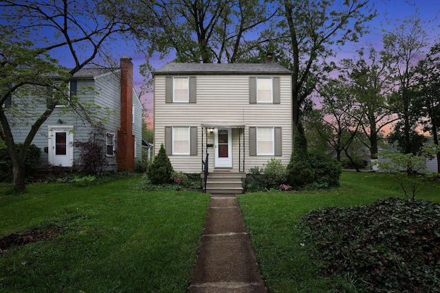 view of front facade with a yard and a chimney