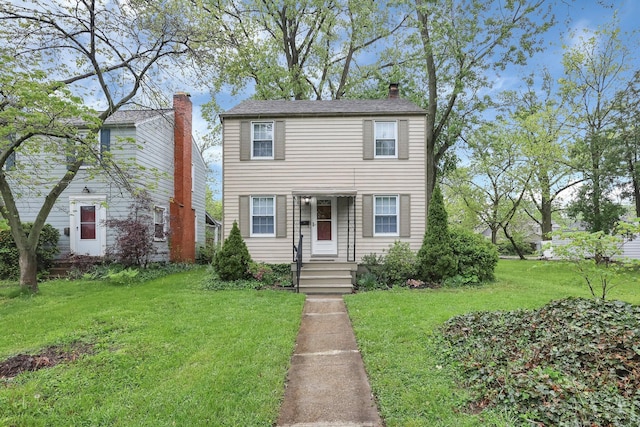 colonial-style house featuring a front lawn and a chimney