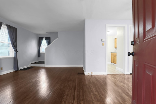 unfurnished living room with wood finished floors and baseboards
