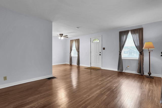 unfurnished living room with healthy amount of natural light, wood finished floors, and baseboards