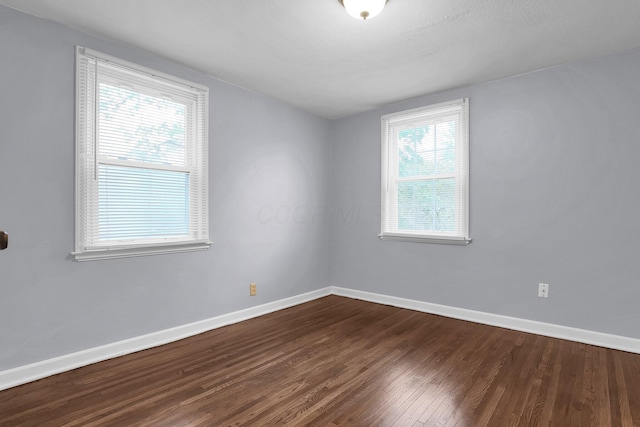 unfurnished room with dark wood-type flooring and baseboards