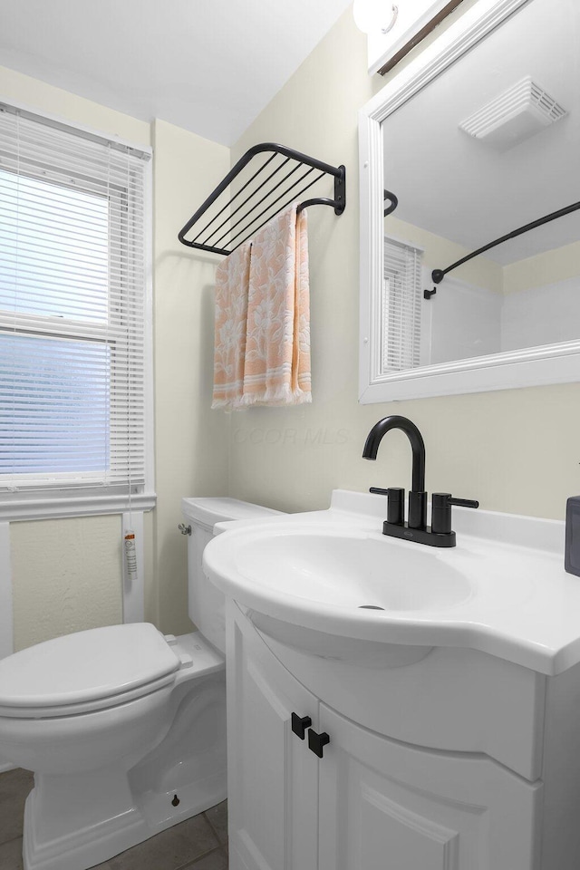 bathroom featuring toilet, plenty of natural light, vanity, and tile patterned floors