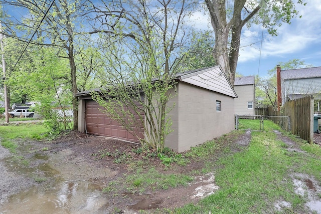 view of home's exterior featuring fence, concrete block siding, a detached garage, a gate, and an outdoor structure