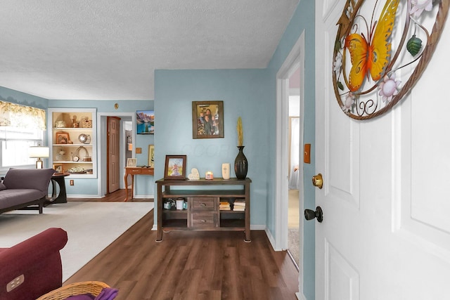 entrance foyer with a textured ceiling, dark wood-style flooring, and baseboards