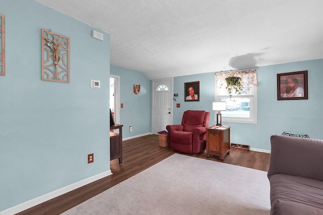 living area featuring wood finished floors, a textured ceiling, and baseboards