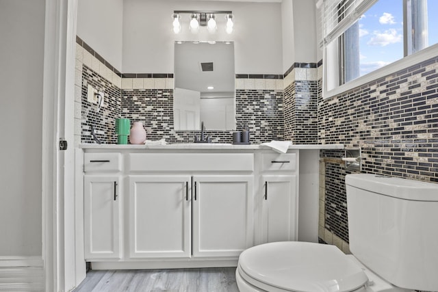 838 Wilson Ave, Columbus, OH 43206 - bathroom with toilet, tile walls, vanity, a wainscoted wall, and wood finished floors