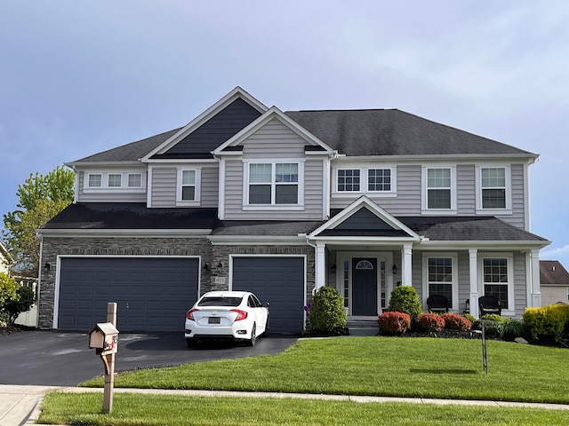 craftsman-style home with a garage, roof with shingles, driveway, and a front lawn